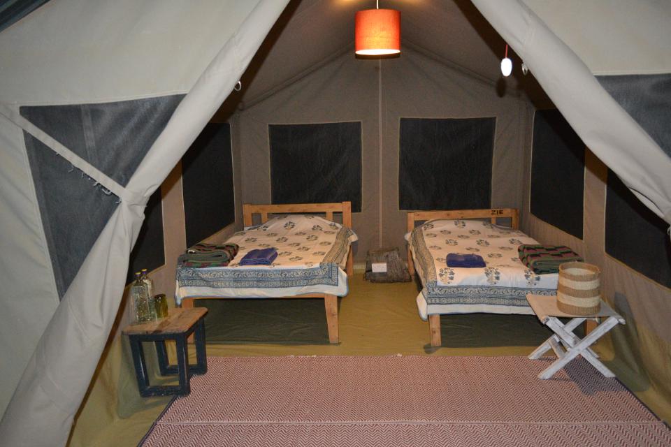 A double bed made up inside a safari tent.