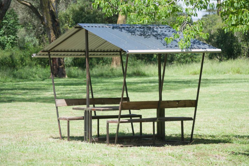 An open picnic shelter on a green lawn.