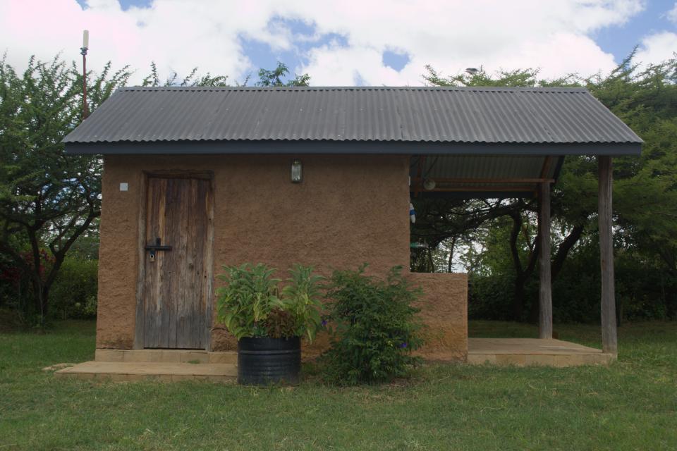 A small stone bathroom block with a porch.