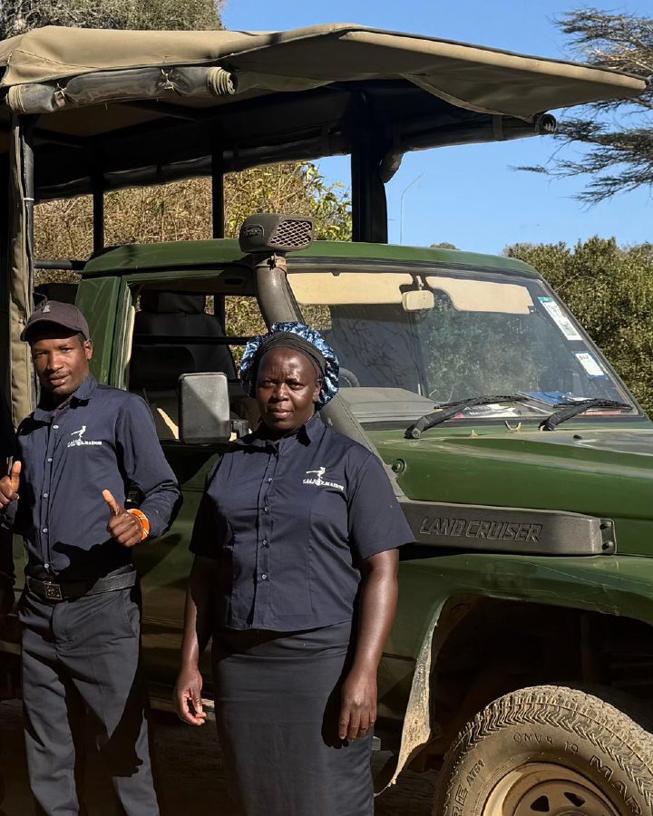 Regina standing with the Ol Maisor team beside a safari vehicle.